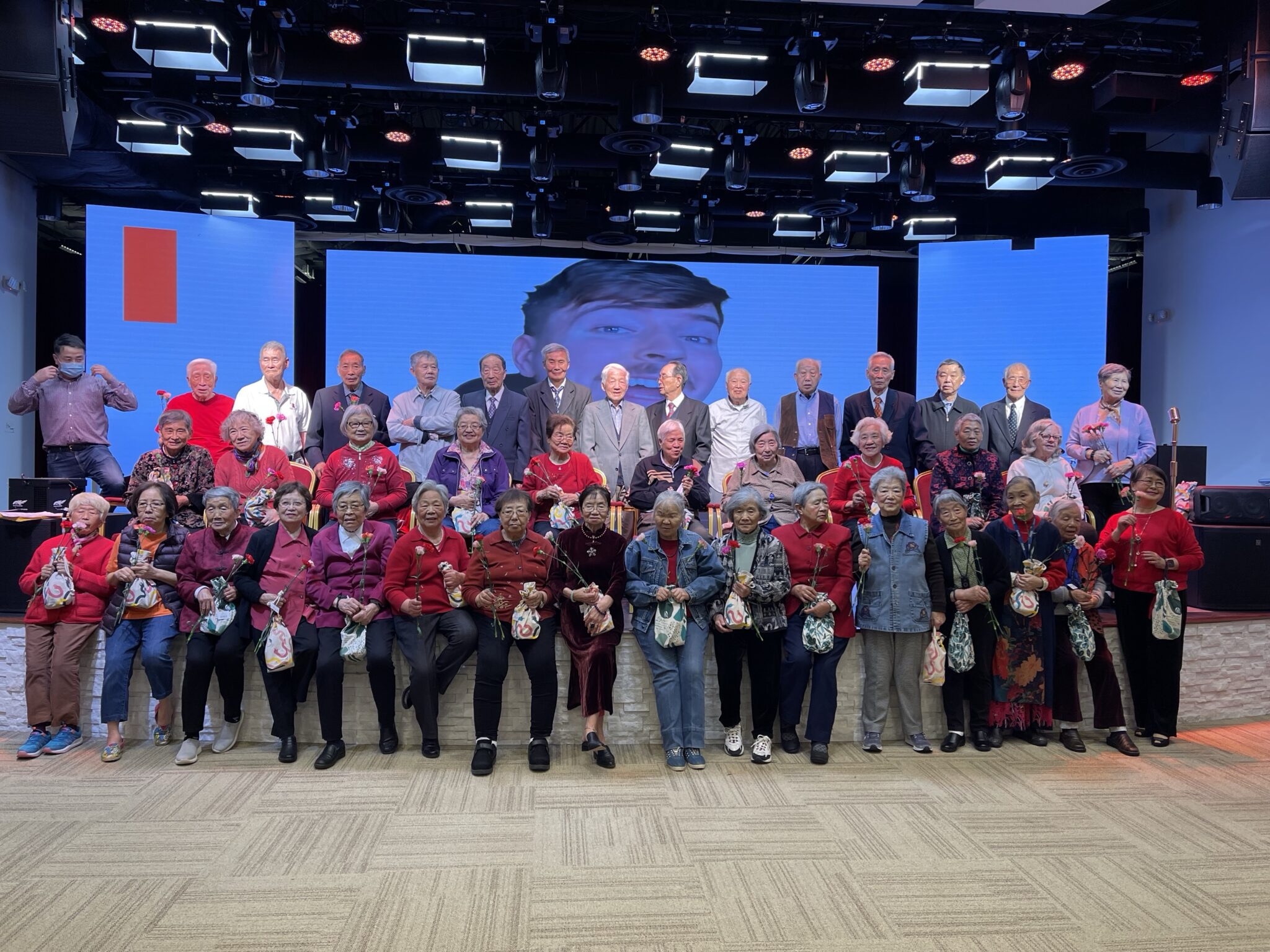 Seniors gathered on stage with roses after a program at Le Yuan