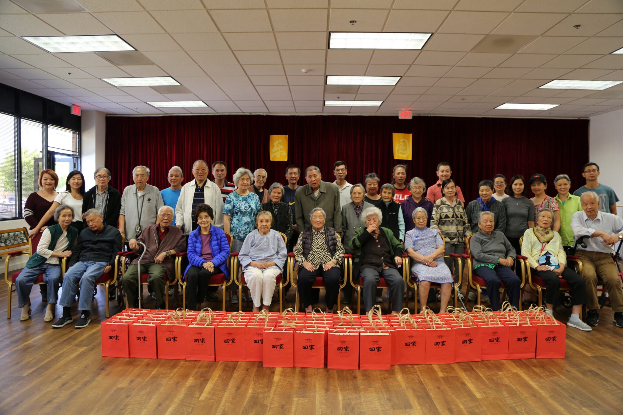 Seniors and staff posing together before a trip, with gift bags lined up