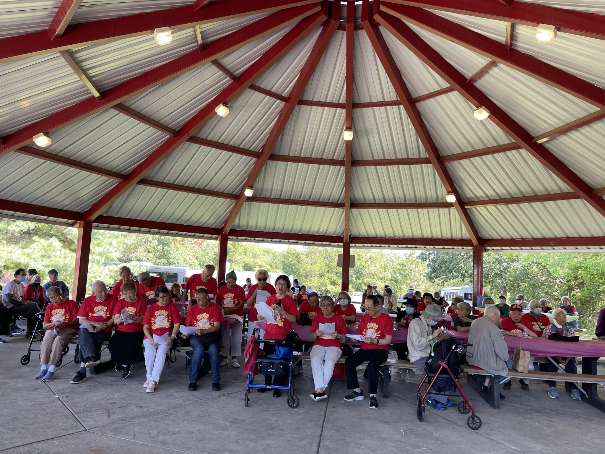 Seniors singing together at an outdoor pavilion gathering